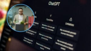 Na zdjęciu jest monitor z panelem głównym ChatGPT. W kółku w lewym górnym rogu jest mężczyzna w okularach pakujący swoje rzeczy do kartonu.