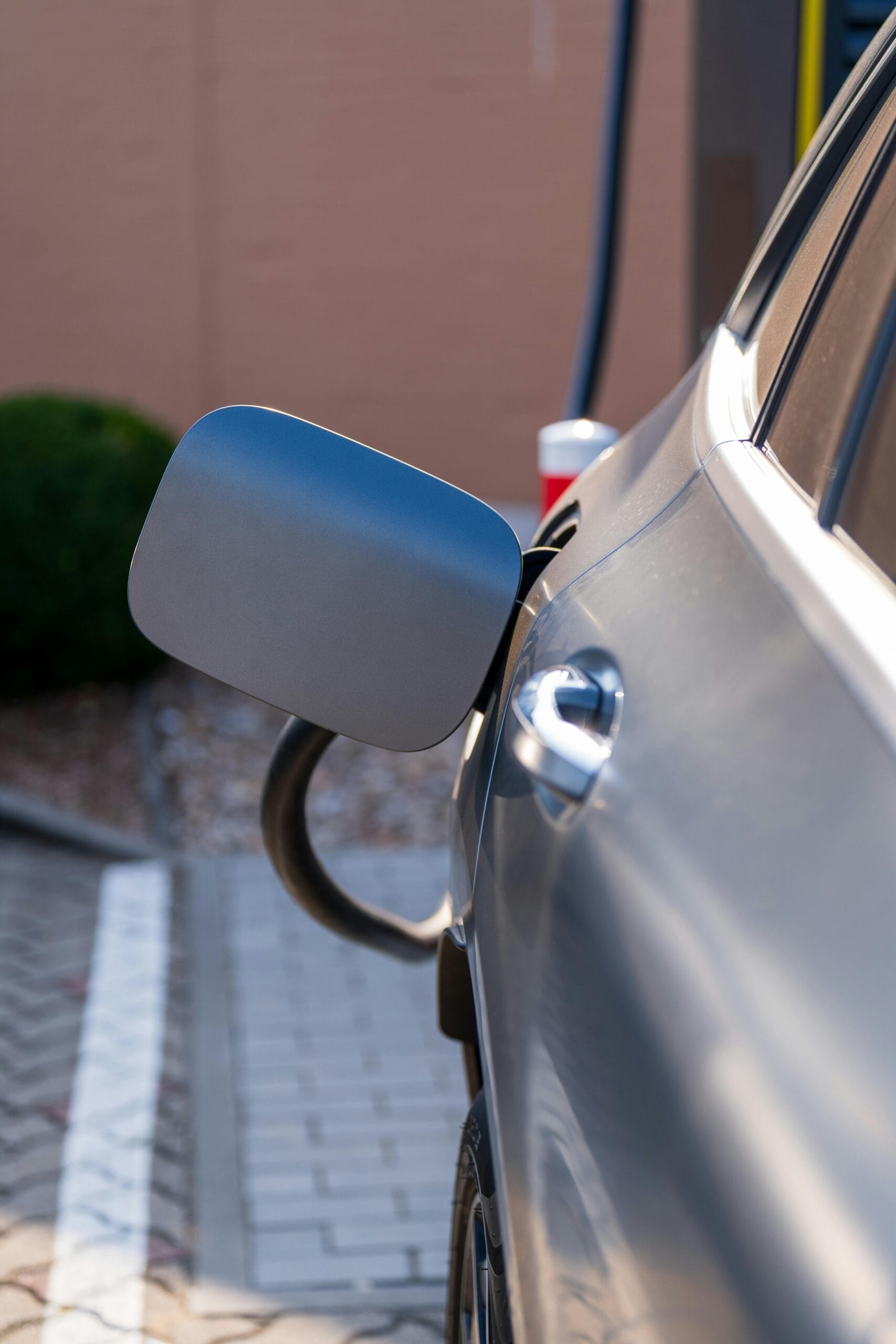 Samochód elektryczny ładujący się przy murze z podłączoną ładowarką