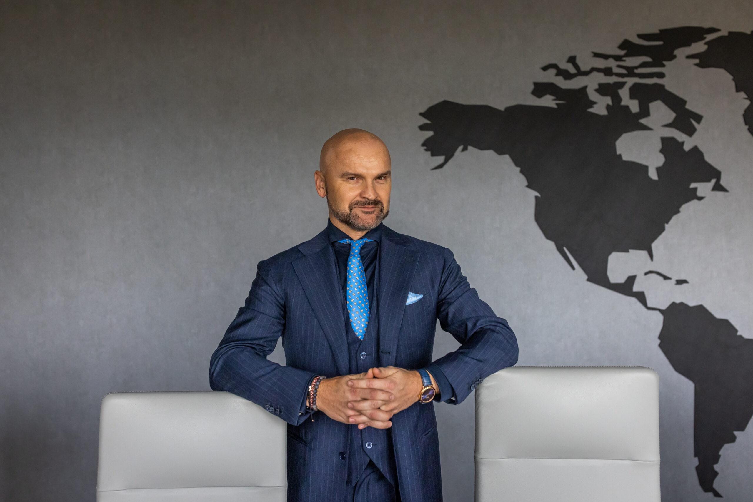 Rafał Brzoska, prezes InPostu w garniturze przy biurku.