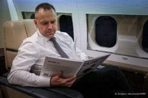 Karol Nawrocki w koszuli czytający w samolocie.