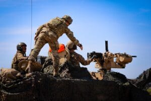 Żołnierze w mundurach i kamizelkach pracujący na czołgu typu Abrams.