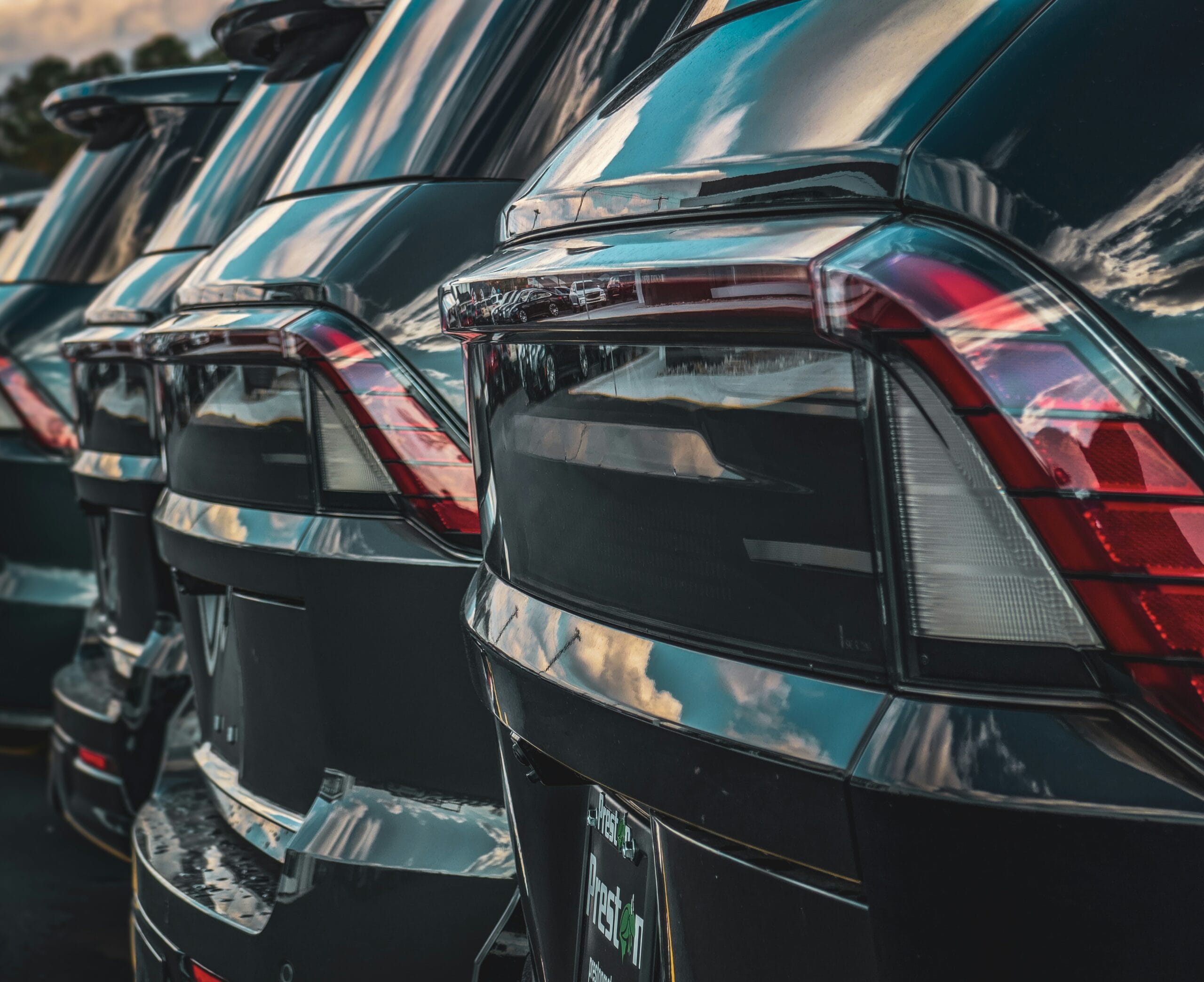 Zdjęcie przedstawia tyły ustawionych w rzędzie czarnych samochodów