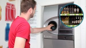 Mężczyzna w czerwonej bluzce korzysta z automatu zwrotnego. W prawym górnym rogu jest kółko, w którym znajduje się drugie zdjęcie przedstawiające butelki wódki na półce sklepowej.