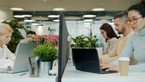 Pracownicy - kobiety i mężczyźni elegancko ubrani - w biurze przy komputerach.