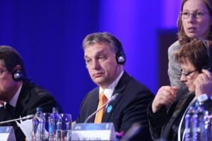 Victor Orban w garniturze podczas posiedzenia w Parlamencie Europejskim. Na uszy ma nałożone słuchawki