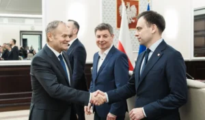 Uścisk dłoni Donalda Tuska i Andrzeja Domańskiego w Kancelarii Premiera. W tle przygląda się temu Jan Grabiec