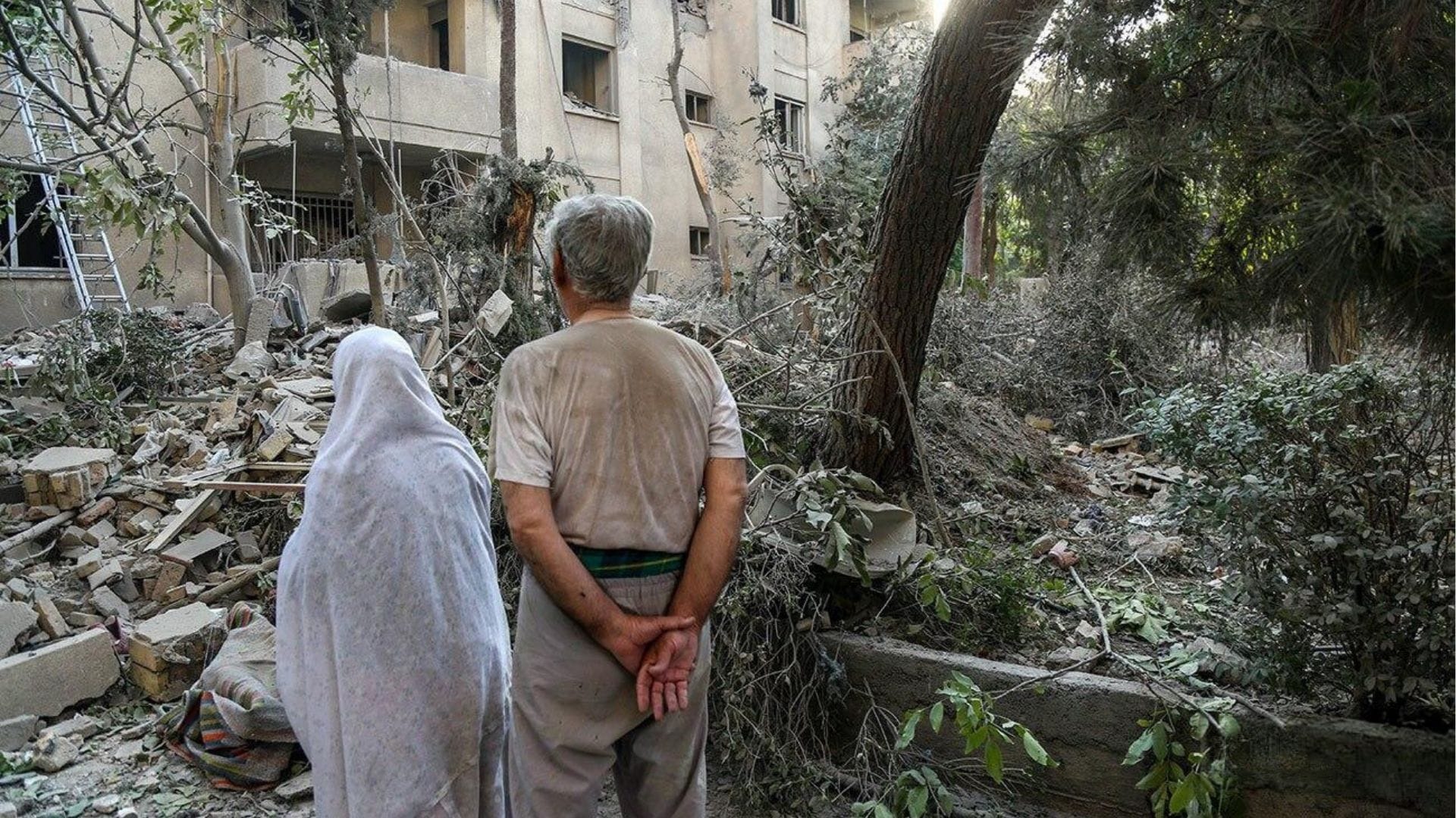 Zdjecie przedstawia małżeństwo patrzące na gruzy domu