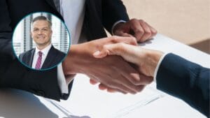 Podpisanie umowy, uścisk dłoni. W lewym rogu jest kółko z twarzą Piotra Matczuka.