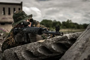 Żołnierz z bronią w zasiekach na tle pochmurnego nieba