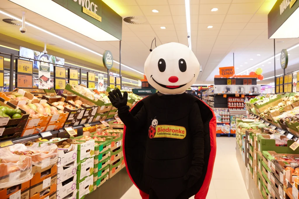 Maskotka Biedronki w sklepie sieci na tle półek