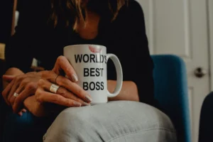Kobieta trzyma kubek ubrudzony szminką z napisem "World's best boss"