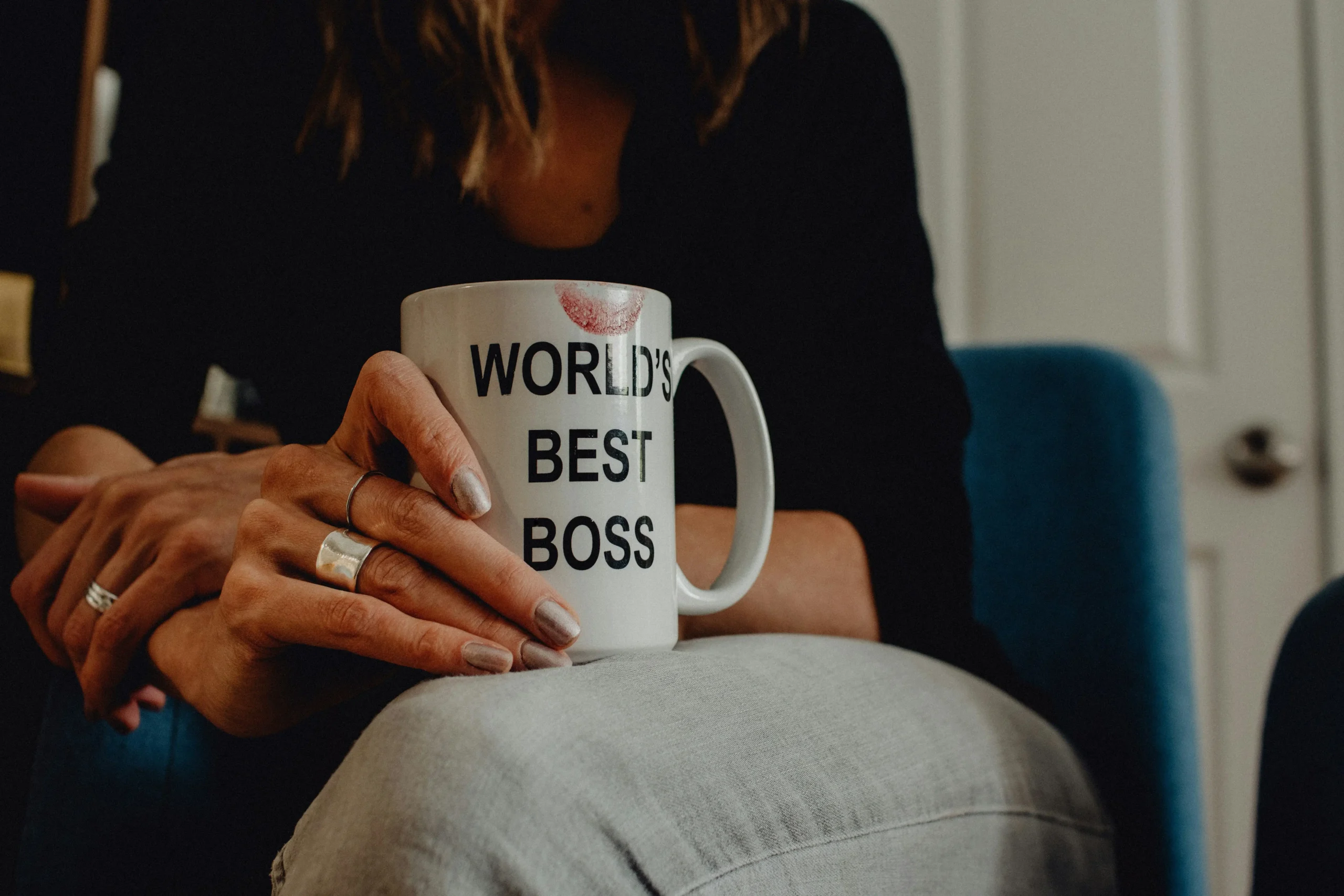 Kobieta trzyma kubek ubrudzony szminką z napisem "World's best boss"