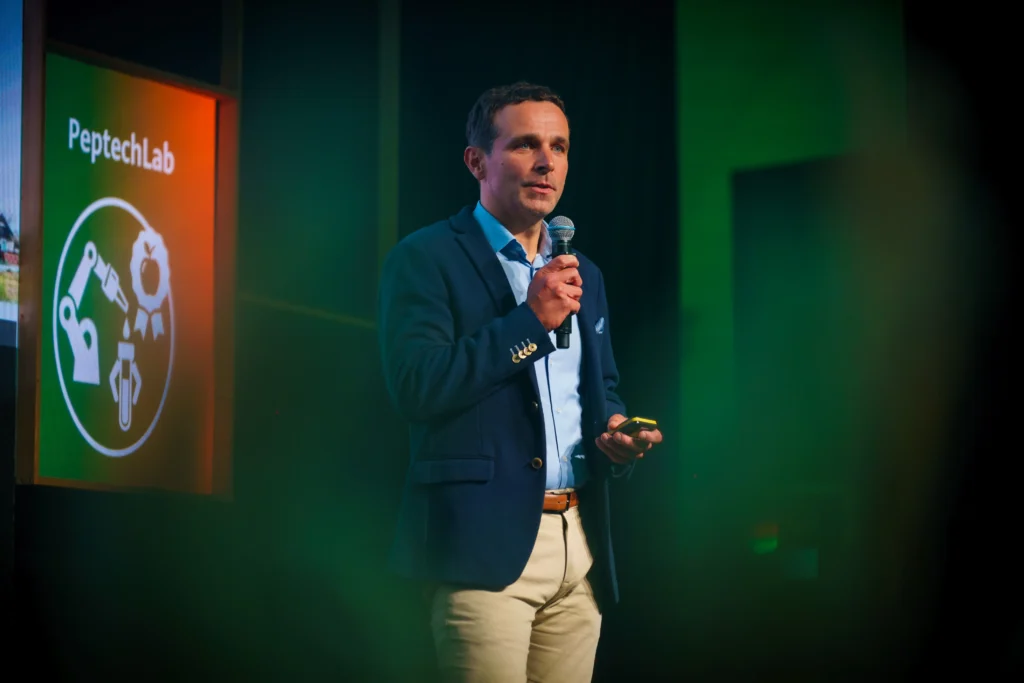 Adam Penkala w garniturze przemawia na konferencji Huawei Startup Challenge.