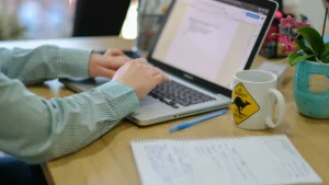 Osoba pisząca na laptopie.